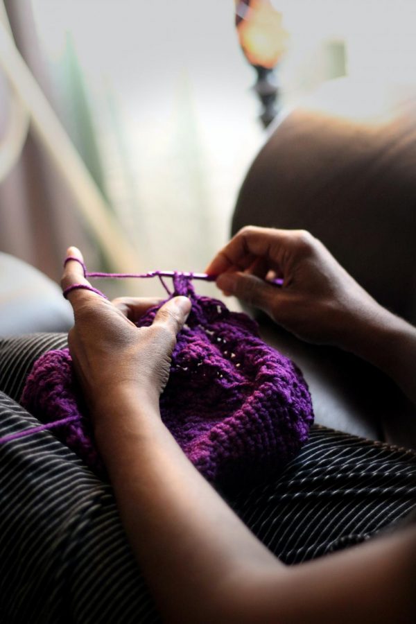 A person crocheting with purple yarn.